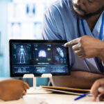 Team of young nurses learning the practice from a doctor expert in the cabinet, emphasizing health care management and diagnostics in a facility. African american residents examine x rays.