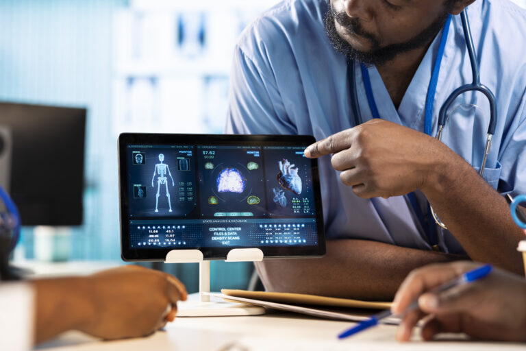 Team of young nurses learning the practice from a doctor expert in the cabinet, emphasizing health care management and diagnostics in a facility. African american residents examine x rays.